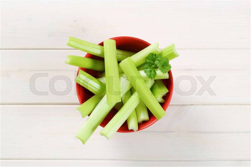 Bowl of green celery stems on white wooden background, stock photo