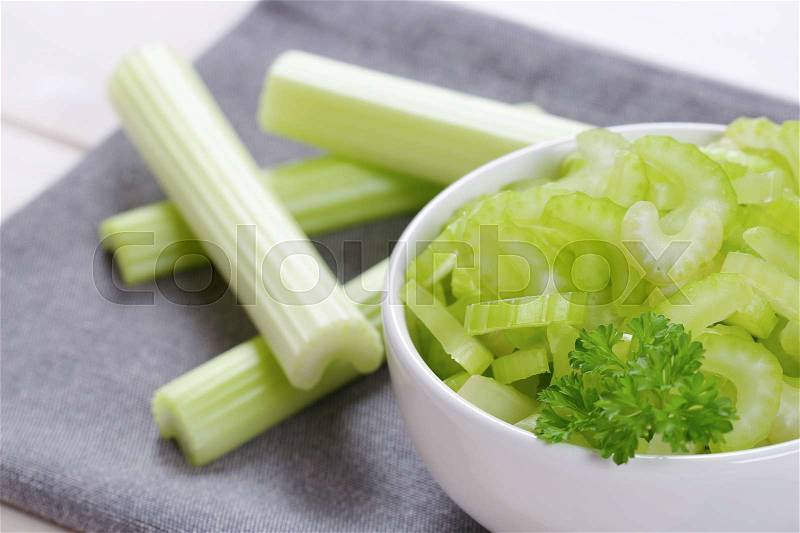 Bowl of chopped celery stems on grey place mat - close up, stock photo
