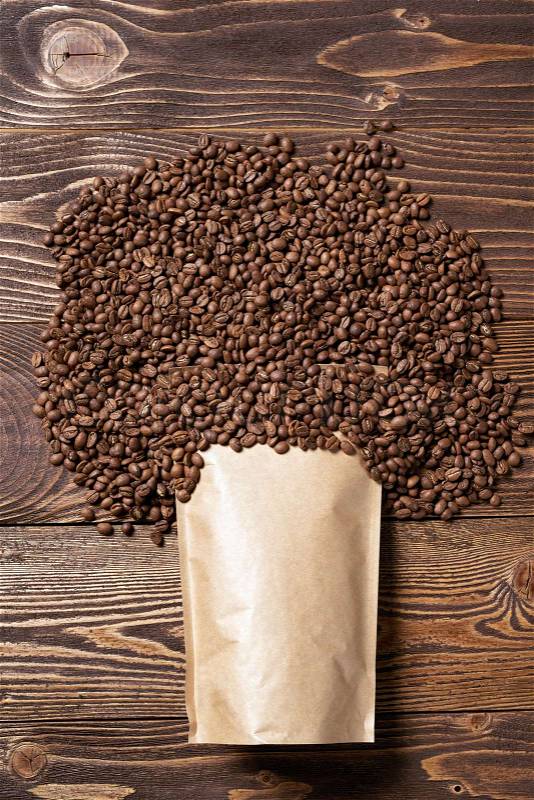 Mock-up craft paper pouch bag top view over wooden background with coffee beans over, stock photo