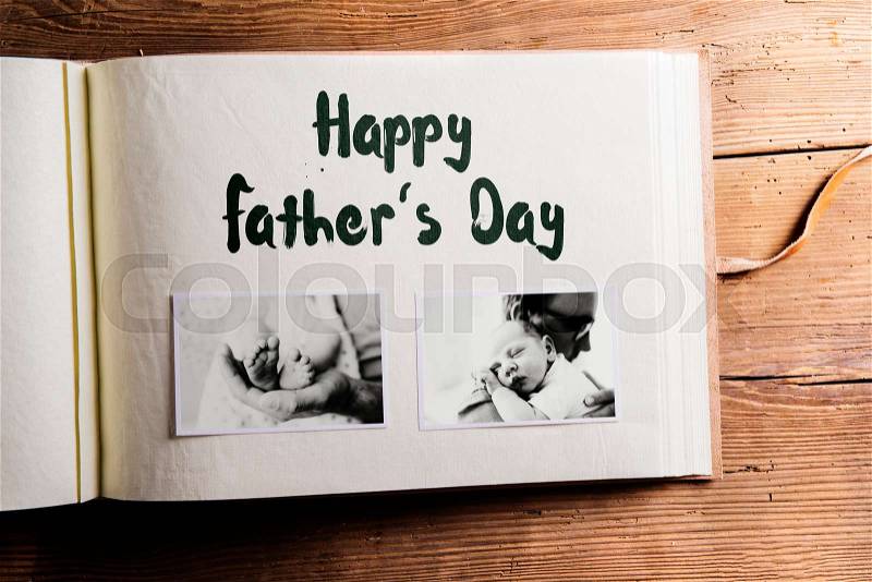 Photo album with pictures of young father and his cute newborn baby son. Fathers day concept. Studio shot on woden background, stock photo