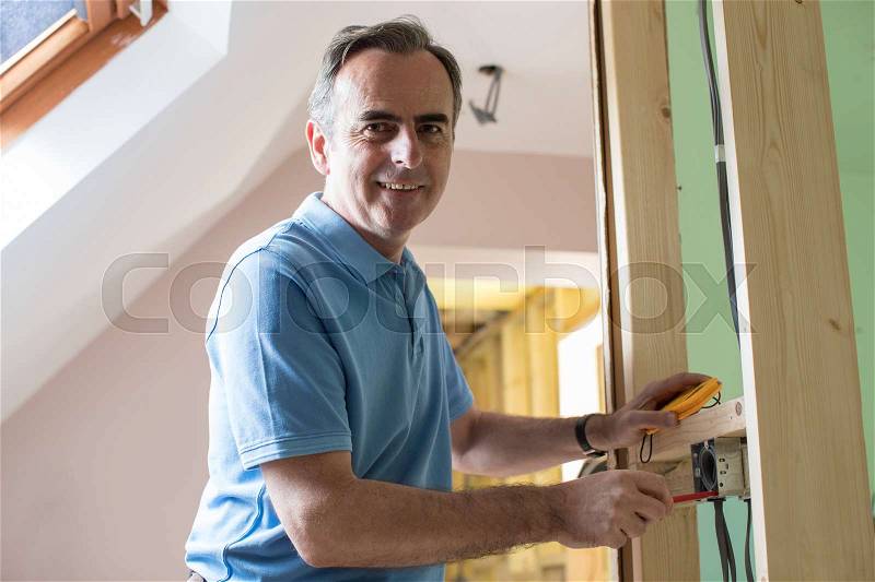 Portrait Of Electrician Installing Socket In New House, stock photo