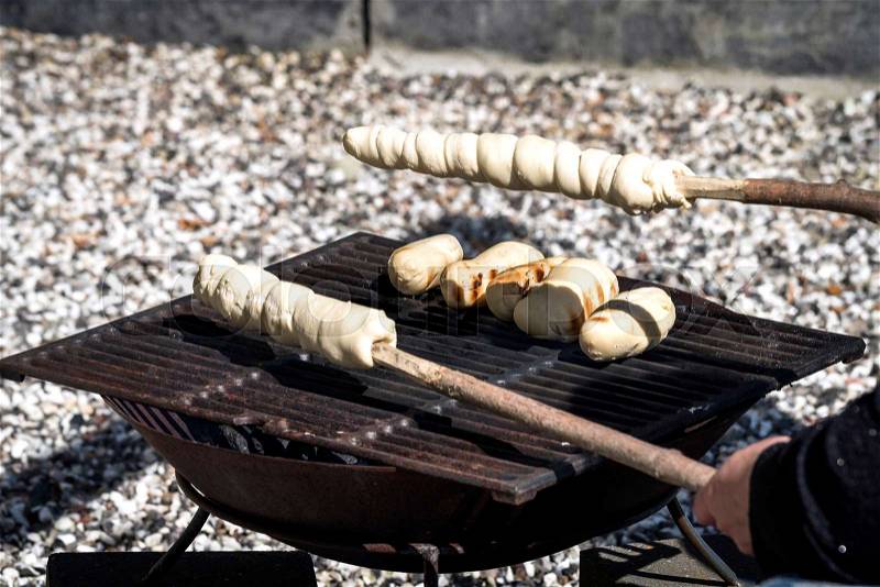 Bread on an outdoor grill with raw dough on a stick ready to be baked, stock photo