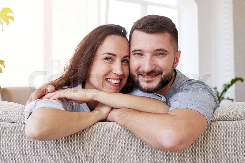 Mid shot of beautiful woman and man hugging and relaxing on sofa, stock photo