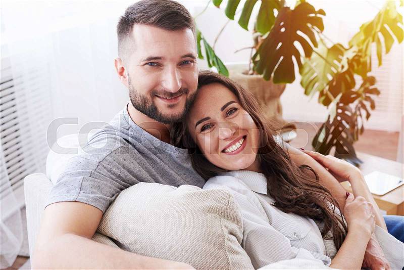 Mid shot of gorgeous girl and guy hugging and relaxing on sofa, stock photo