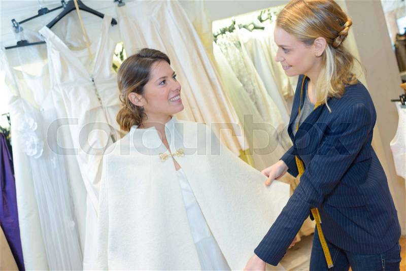 Woman choosing wedding dress in clothes shop, stock photo