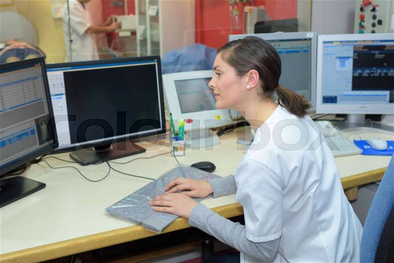 Female nurse working on computer at hospital reception, stock photo