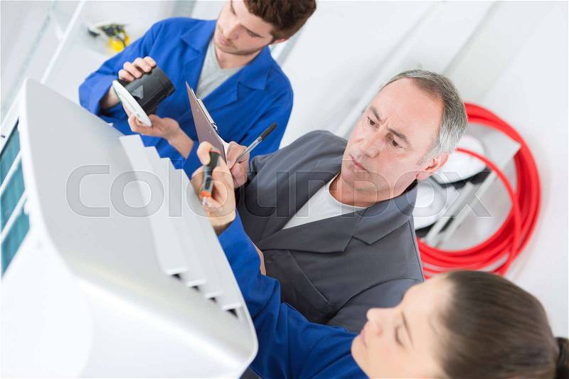 Apprentices fixe an industrial compressor unit as his supervisor watches, stock photo