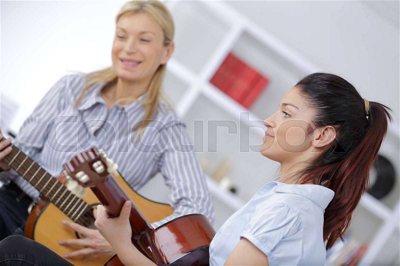 Mother and daughter playing guitar together, stock photo