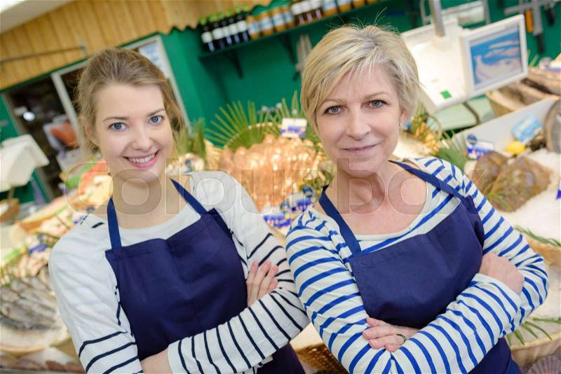 Smiling sales assistants working at counter in fish store, stock photo