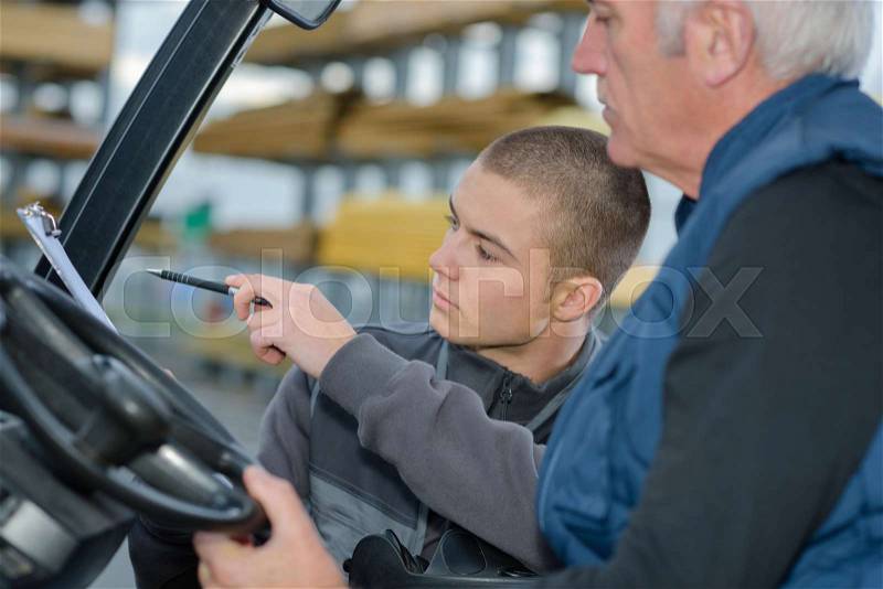 Teacher helping student training to be car mechanics, stock photo