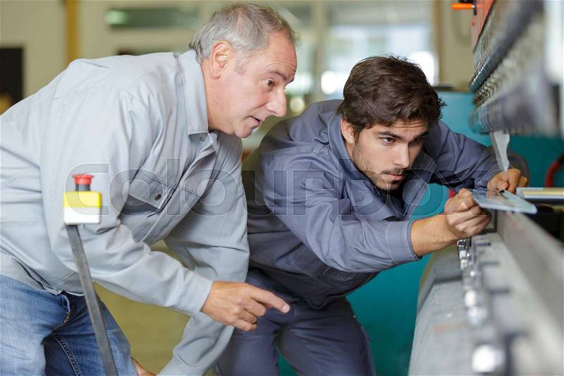 Apprentice mechanical technician measuring cutting tool at tool workshop, stock photo