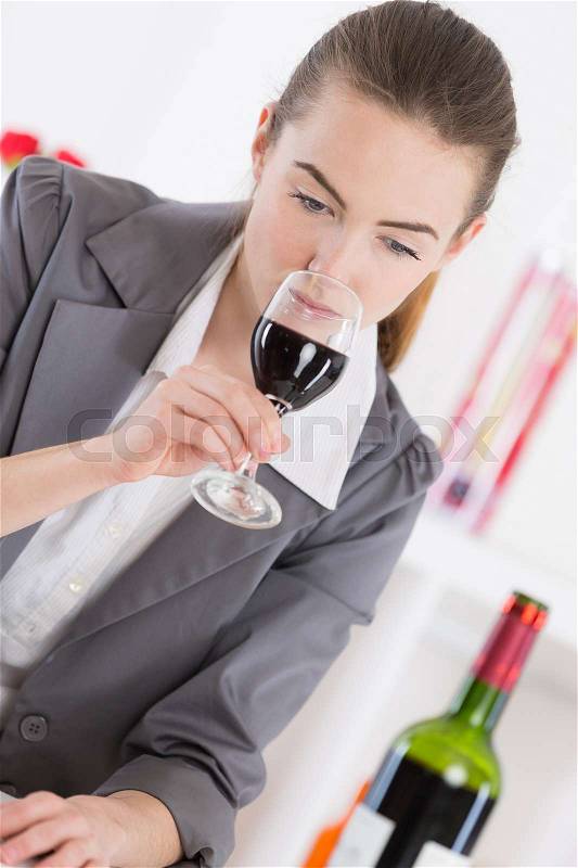 Woman sniffing red wine in a glass close up, stock photo
