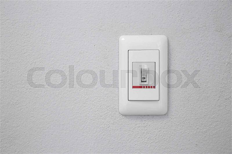 Wall light switch in the on position, stock photo
