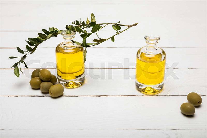 Close-up view of pure olive oil and green olives on wooden surface, stock photo