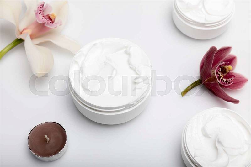 Close-up view of organic cream in containers with orchids and candle isolated on white , stock photo