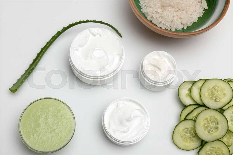 Top view of facial cream in containers, cucumber slices and aloe vera plant isolated on white, stock photo