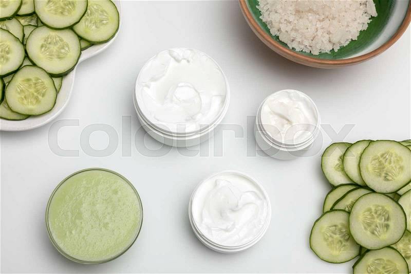 Top view of facial cream in containers and cucumber slices isolated on white, stock photo