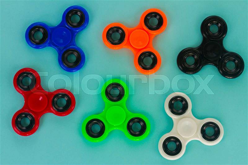 Fidget spinners on blue background, popular relaxing toy, generic design, stock photo