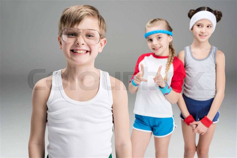 Cute smiling sporty girls looking at happy boy in sportswear, children sport concept, stock photo