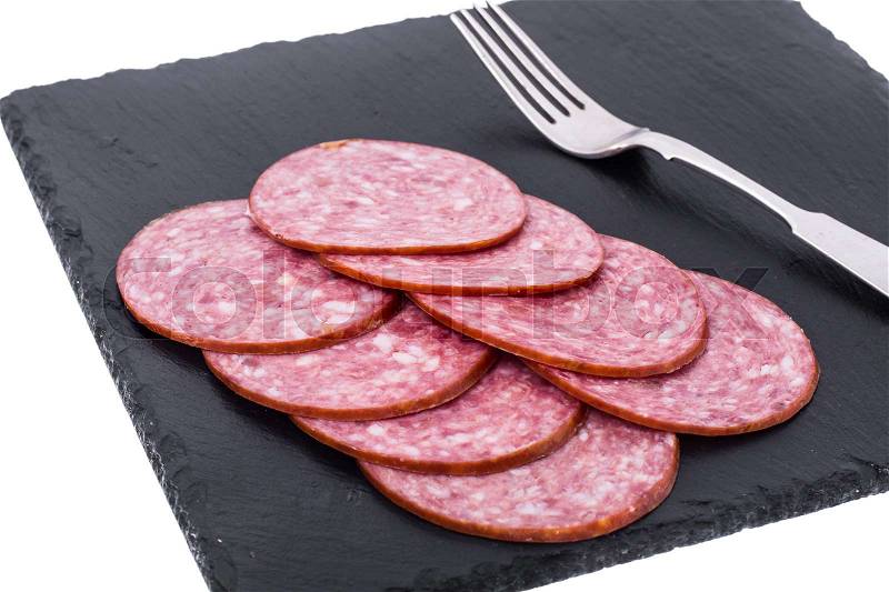 Sliced sausage on black stone plate. Studio Photo, stock photo