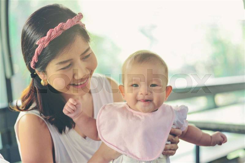 Asian happy mom holding happy baby girl. Vintage effects, soft focus and soft light, stock photo