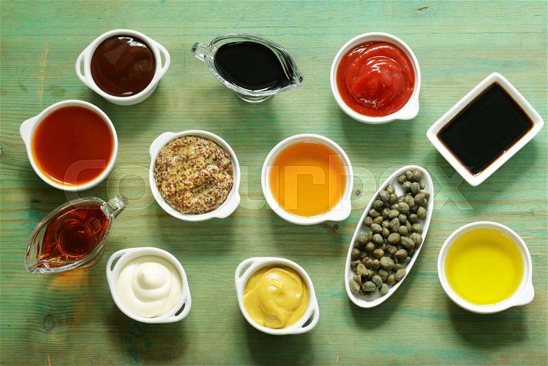 Different types of sauces and oils in bowls, top view, stock photo