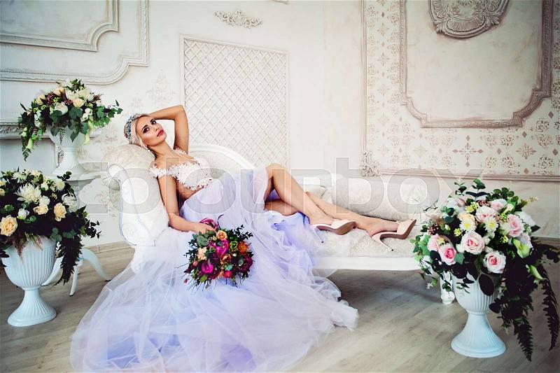 Beautiful Sexy Model Woman in Evening Gown with Tulle Skirt Relaxing on the Sofa, stock photo