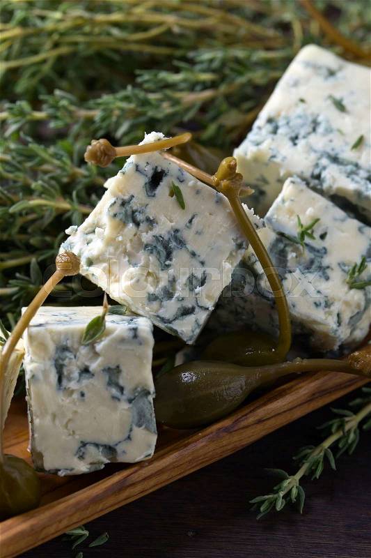 Blue cheese , capers and branches of thyme on a wooden table , stock photo