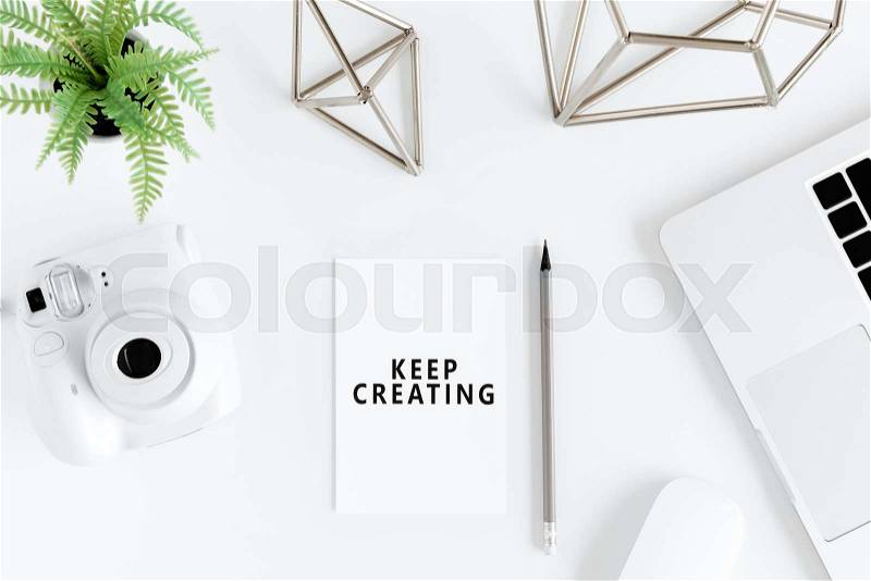 Top view of keep creating motivational quote and instant camera at workplace, stock photo