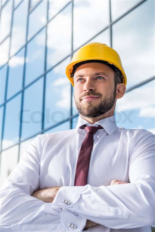 Portrait of smiling professional architect in hard hat against building, stock photo