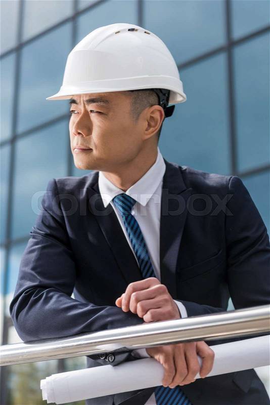 Portrait of professional architect in hard hat holding blueprint, stock photo