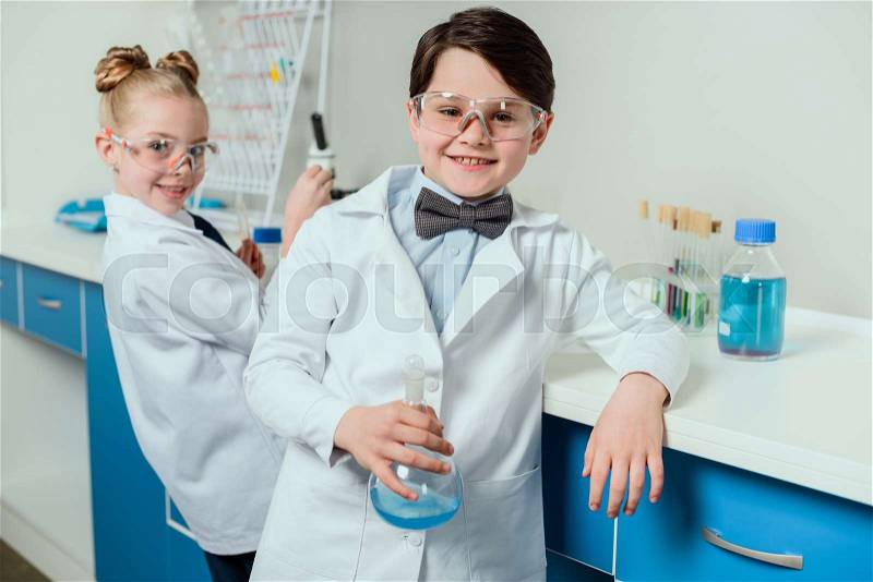 Schoolchildren with science lab equipment in chemical lab, scientists kids team concept, stock photo
