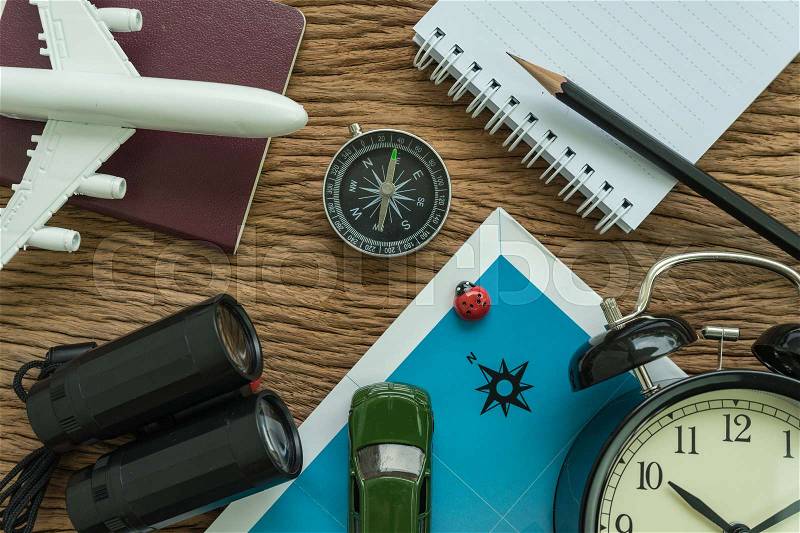 Travel planning concept with airplane, passport, compass, binoculars, toy car, pencil and paper note on wood table, stock photo