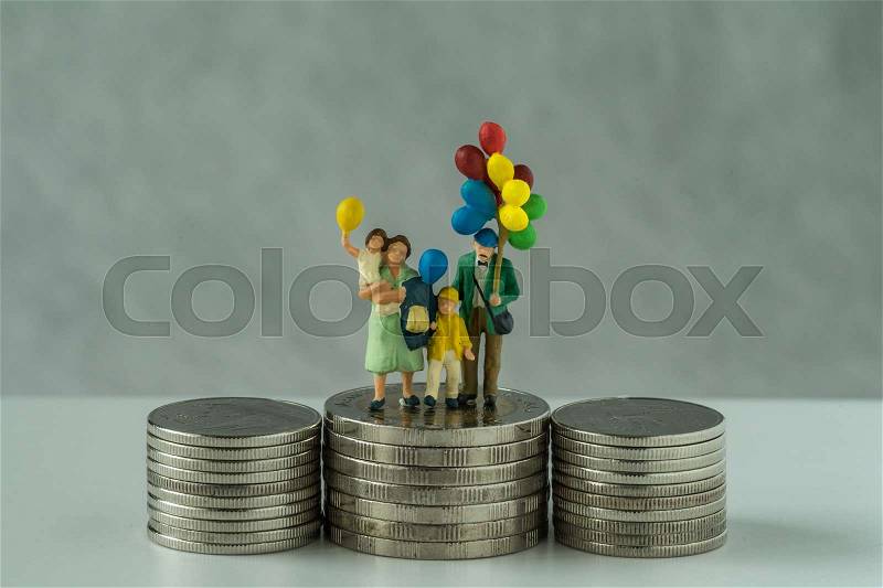 Miniature figure family with balloon standing on stack of coins as financial business or happy retirement concept, stock photo