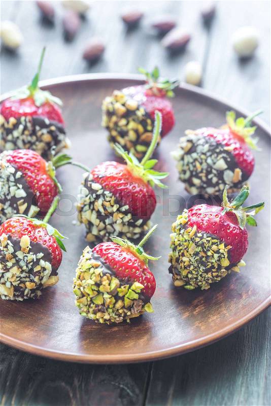 Fresh strawberries covered with dark chocolate and nuts, stock photo