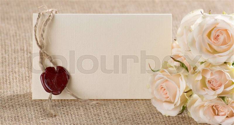 Floral background with cream roses and postcard with place for your text and red wax seal on sackcloth , stock photo
