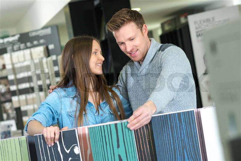 Positive couple looking at flooring in interior store, stock photo