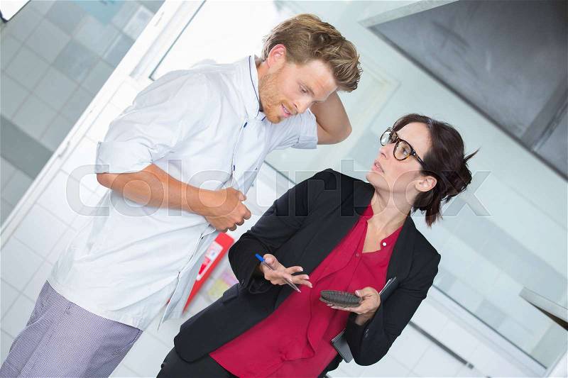 Restaurant manager talks to chef about reservations, stock photo