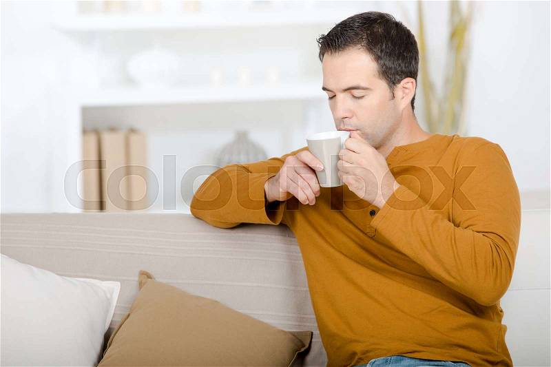 Guy sniffing aroma of coffee, stock photo