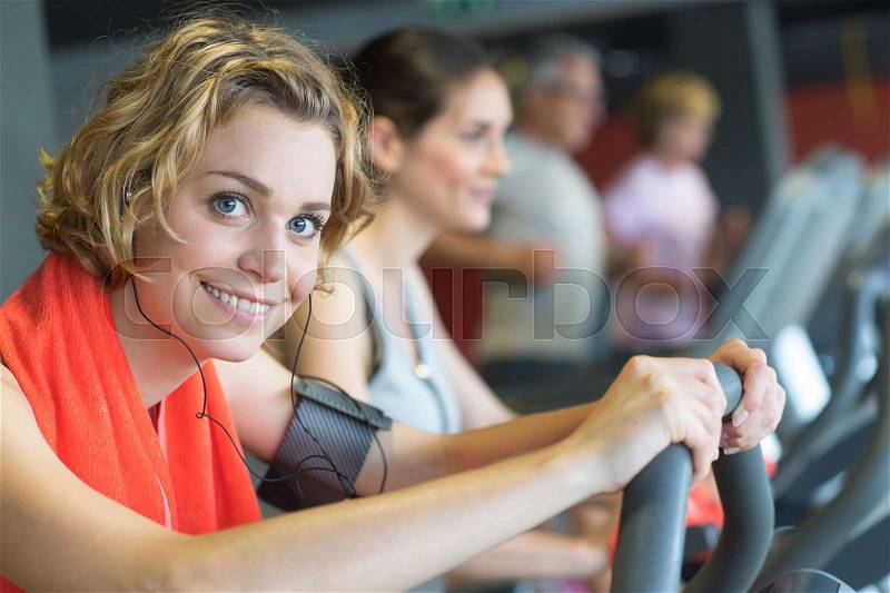 People training on exercise bike in gym, stock photo