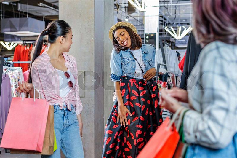 Multicultural hipster girls choosing clothes in boutique, fashion shopping girls concept , stock photo