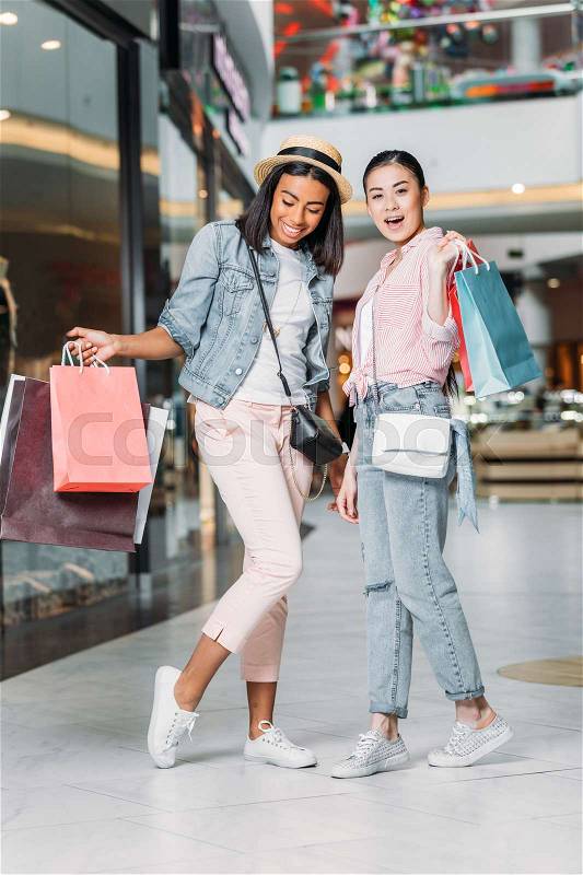 Stylish women friends shopping together at shopping mall, stock photo