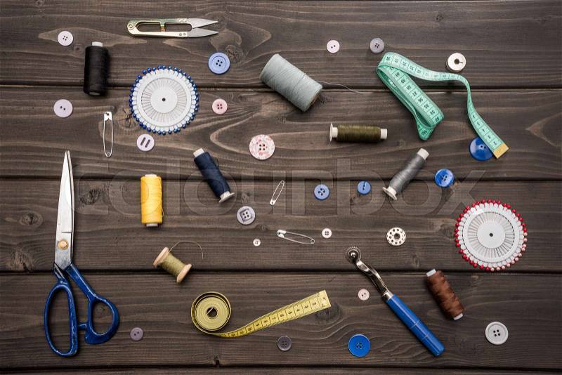 Top view of set of various sewing supplies on wooden surface, stock photo