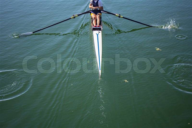 A young girl rowing in boat on water, stock photo