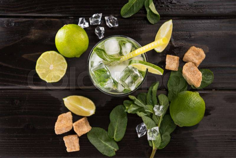 Top view of mojito cocktail in glass and fresh ingredients on dark wooden table top, cocktail drinks concept, stock photo