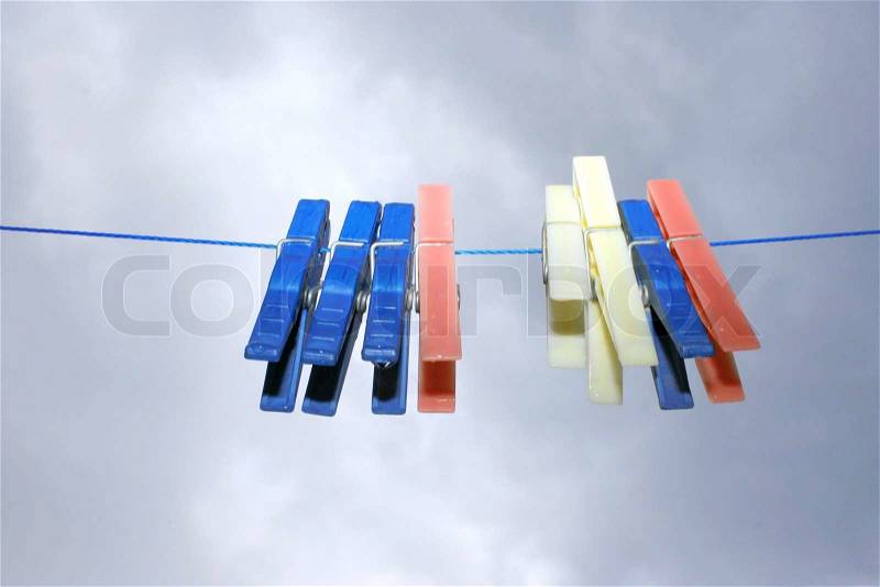 Colorful clothespins with rain drops on the rope on the sky background, stock photo