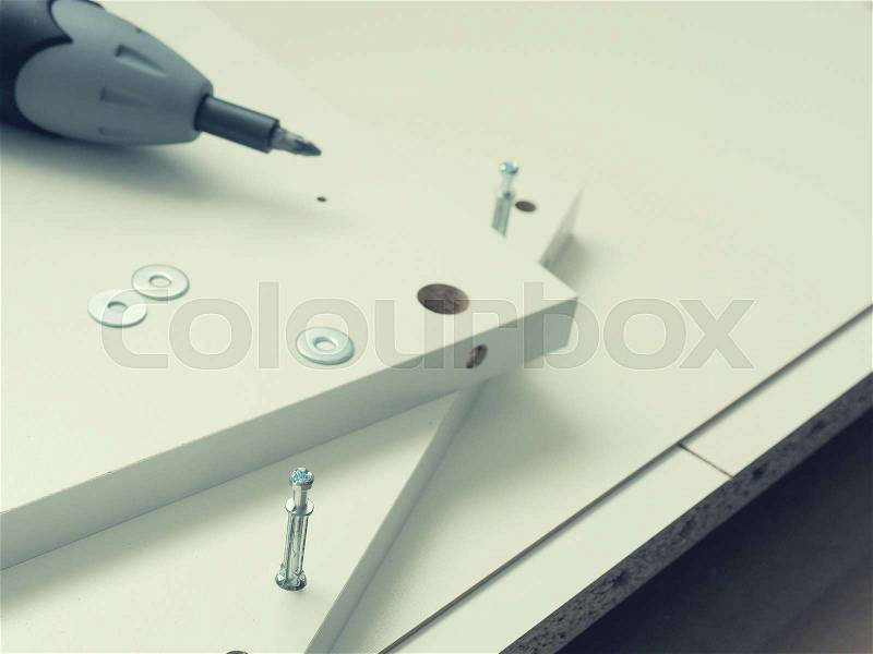 Close up of white furniture parts with cordless screwdriver, mounting furniture, stock photo
