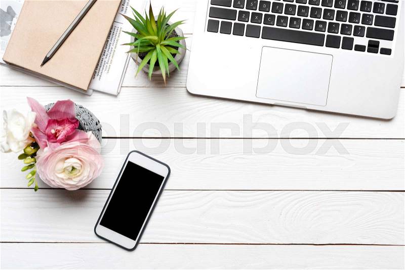 Top view of laptop, smartphone and beautiful flowers in vase on desk , stock photo
