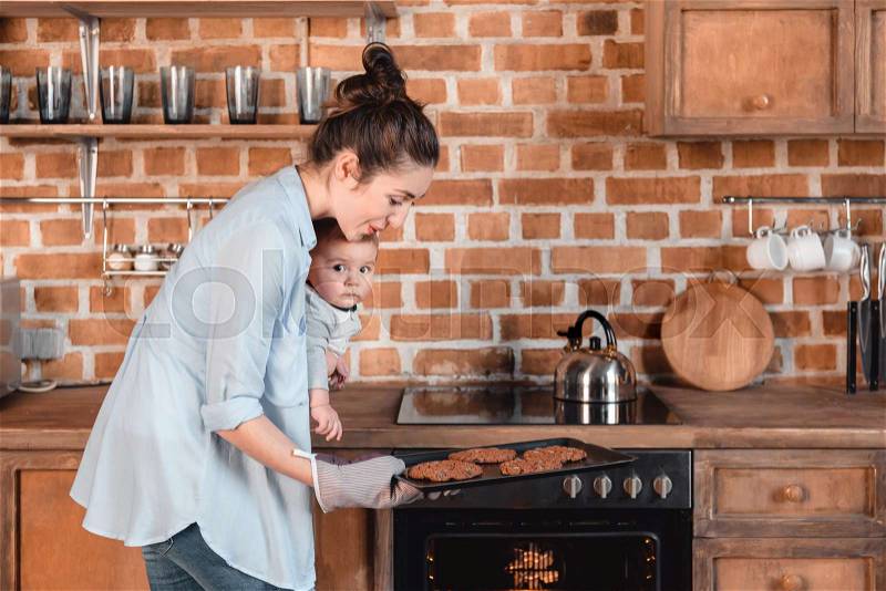 Side view of young woman with her son baking cookies in the kitchen, stock photo
