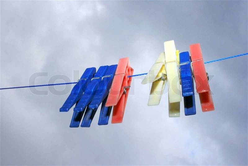 Colorful clothespins with rain drops on the rope on the sky background, stock photo